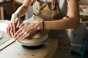 Close up of unrecognizable female artisan shaping handmade bowl on potters wheel, copy space