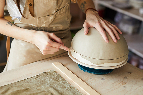 Closeup of unrecognizable female artisan shaping handmade bowl on potters wheel, copy space