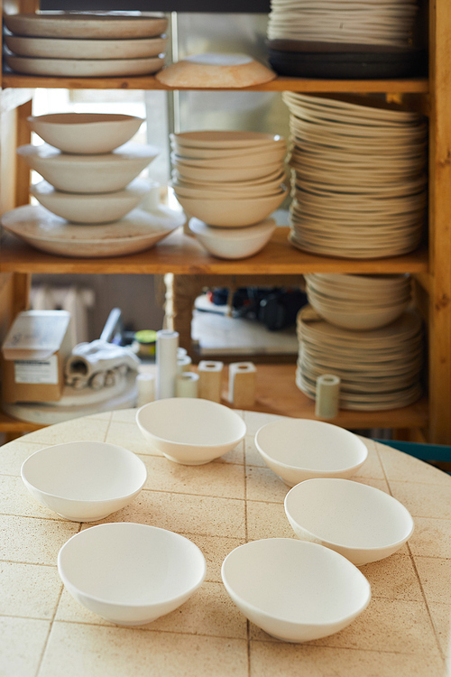 Background image of porcelain bowls on table in artisan studio, copy space