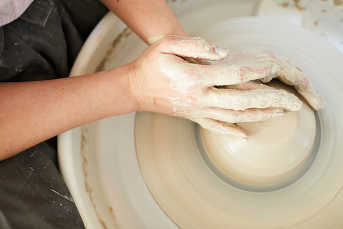 High angle closeup of female potter shaping clay on wheel while working in studio, copy space