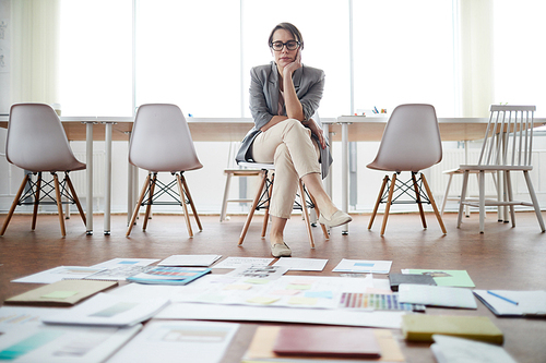 Full length portrait of contemporary businesswoman planning creative project in office with papers laying on floor, copy space