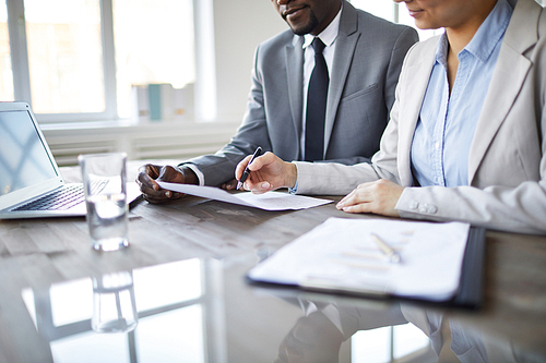 Young confident agent or broker explaining some points of business contract during negotiation with partner