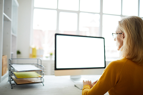 Back view portrait of unrecognizable businesswoman using computer sitting at desk in office, copy space