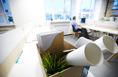 Close-up of cardboard box with clipboard, potted plant, documents placed on office table, dismissal concept
