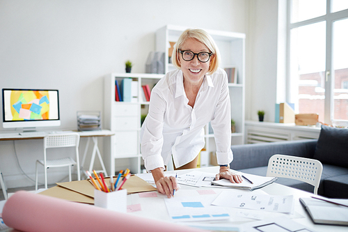 Portrait of smiling mature woman  while working with designs in modern office, copy space