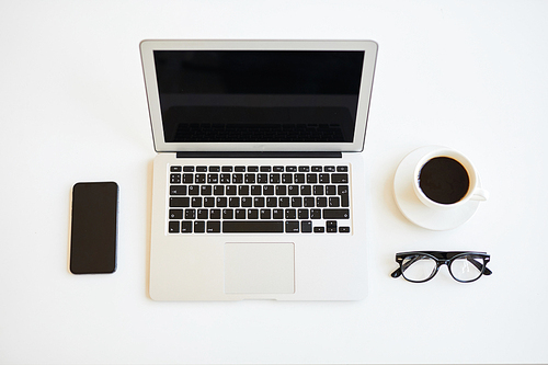Directly above view of minimalistic freelancers desk with open laptop, cup of black coffee, eyeglasses and smartphone, black and white colors