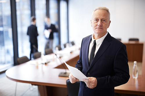 Waist up portrait of senior businessman  standing in conference room, copy space