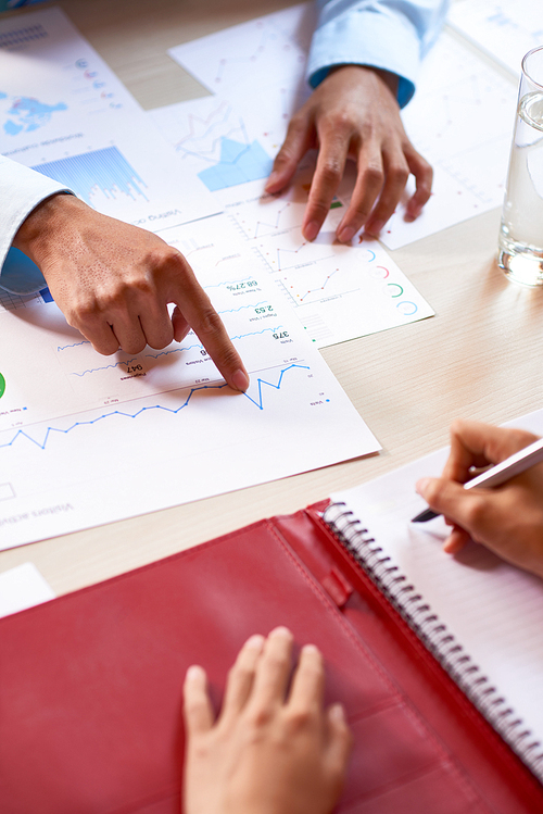 Financial manager discussing sales report with college at daily meeting