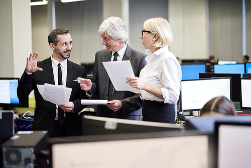 Group of cheerful business people discussing documents standing in office, copy space