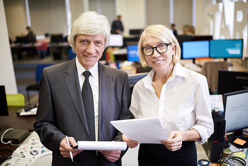 Waist up portrait of two mature business people  standing in modern office, copy space