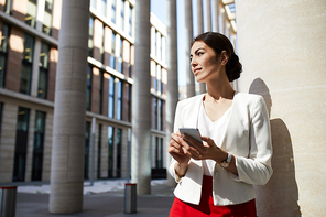 Waist up portrait of elegant young woman looking away pensively while posing outdoors in city, copy space