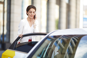 Waist up portrait of beautiful businesswoman opening taxi doorin rush hour in city center, copy space