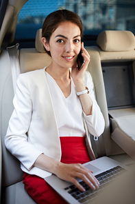 Portrait of successful businesswoman  and speaking by phone in back seat of luxury car, copy space