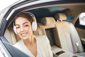 Portrait of beautiful young woman listening to music in taxi and looking at window, copy space