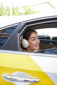 Side view portrait of beautiful young woman listening to music in taxi and looking at window, copy space