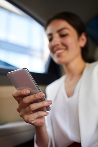 Portrait of smiling businesswoman using smartphone in taxi closeup, copy space