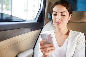 Portrait of smiling businesswoman using smartphone in taxi, copy space