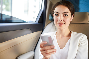 Portrait of smiling businesswoman using smartphone in taxi and , copy space