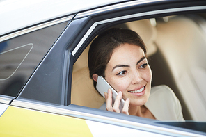 Side view portrait of smiling businesswoman using smartphone in taxi and looking at window