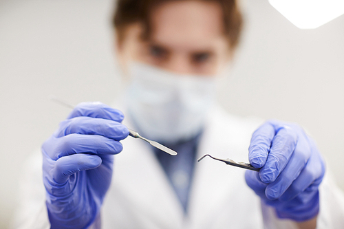 Close up of unrecognizable dentist holding instruments while treating patient, copy space