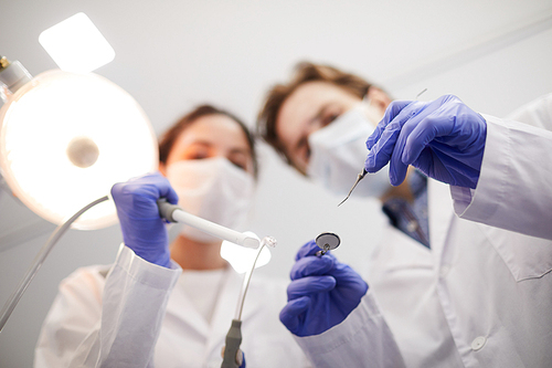 Blurred image of two dentists holding instruments while treating patient, copy space