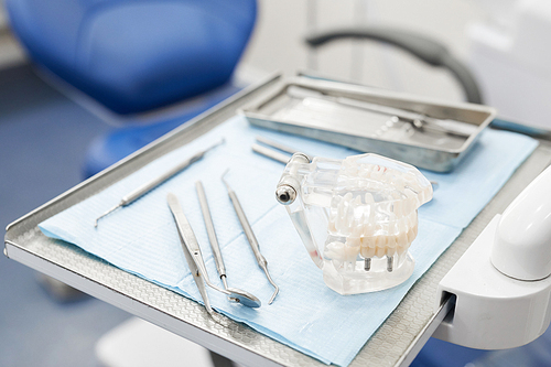 Closeup of teeth model lying on instruments table by dental chair in clinic, copy space