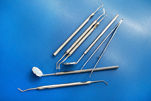 Top view closeup of metal dental tools and instruments lying on table in dentists office, copy space