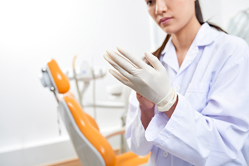Female dentist wearing latex gloves before working with patient