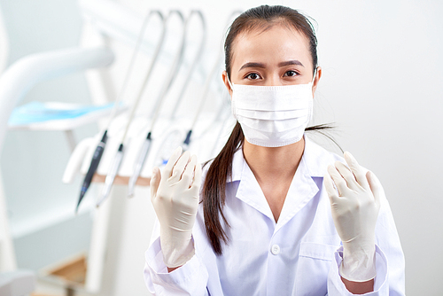 Portrait of young professional dentist in latex gloves and protective face mask