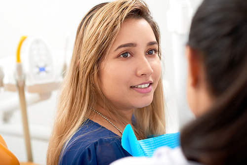 Young Asian woman listening to recommendation of her dentist after check-up