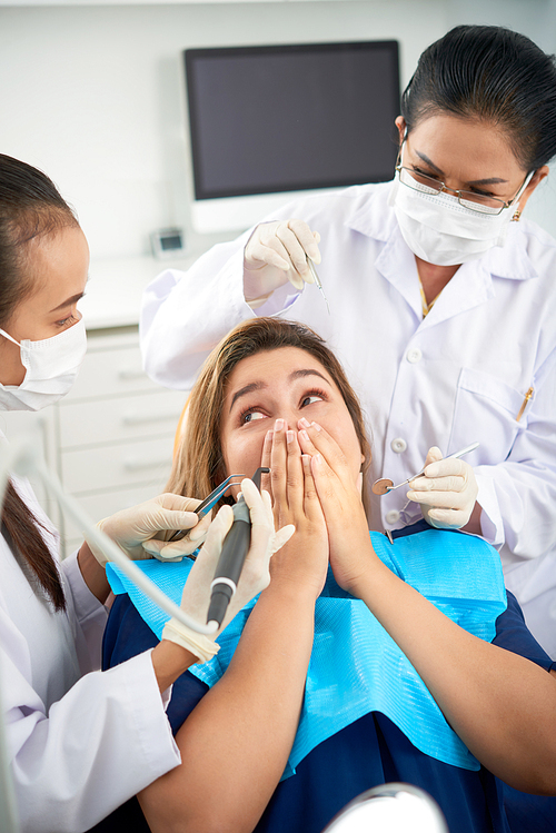 Panicking woman not letting dentists to treat her teeth