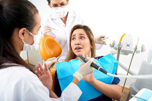Emotional female patient panicking when sitting in dental chair