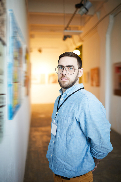 Waist up portrait of modern bearded man posing in art gallery 