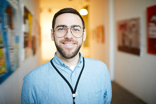 Head and shoulders portrait of smiling bearded man  while posing in art gallery, copy space