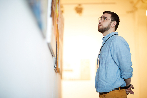 Side view portrait of bearded man looking at pictures in art gallery, copy space