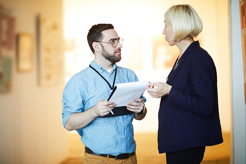 Waist up portrait of man and woman discussing art in museum or gallery, copy space