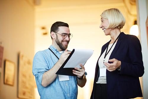 Waist up portrait of two cheerful people discussing art in modern gallery, copy space