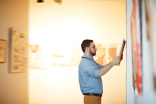 Side view portrait of bearded man holding picture in art gallery or museum, copy space