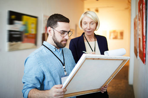 Waist up portrait of modern bearded man buying picture in art gallery or museum, copy space