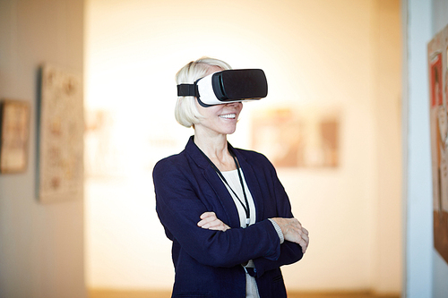 Waist up portrait of smiling modern businesswoman wearing VR headset in art gallery, copy space