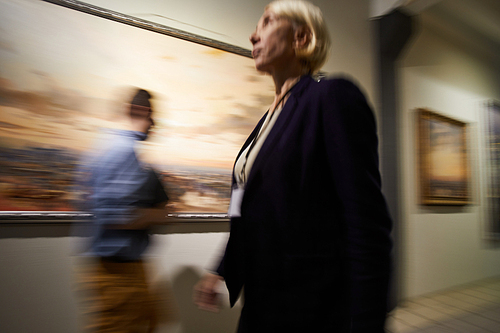 Blurred shapes of people walking in hall of modern art gallery o museum, copy space