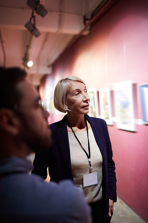 Portrait of two art gallery workers inspecting paintings in museum exhibition