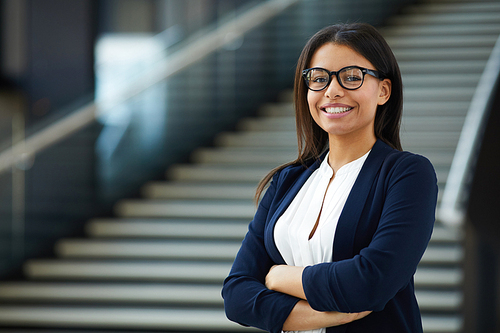 Smiling smart attractive young black lady in glasses standing in lobby and , she working in prosperous company