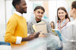 Waist up portrait of group of students chatting during break in college