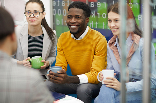 Multi-ethnic group of business people dressed in casual wear chatting in break room