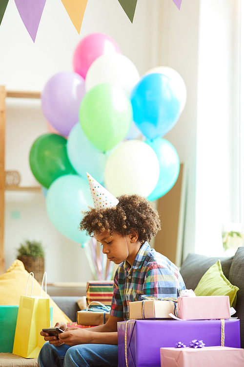 Side view portrait of African-American boy opening presents at Birthday  party, copy space