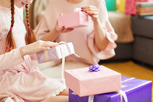 Close up of cute little girl wearing pink opening Birthday presents at party, copy space