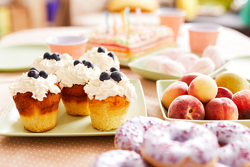 Close up of delicious blueberry cupcakes on table set for kids Birthday party, copy space