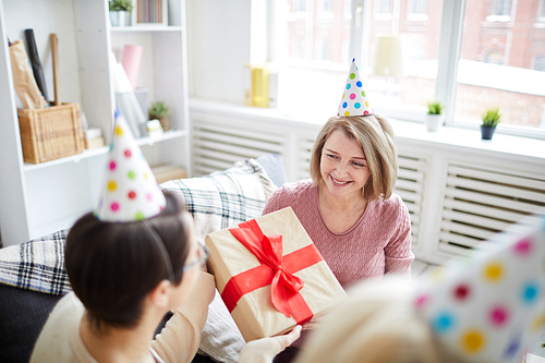 High angle portrait of cheerful women celebrating birthday at home focus on mature woman holding gift box, copy space