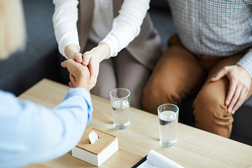 One of young patients shaking hand of counselor over table while being grateful for her advice